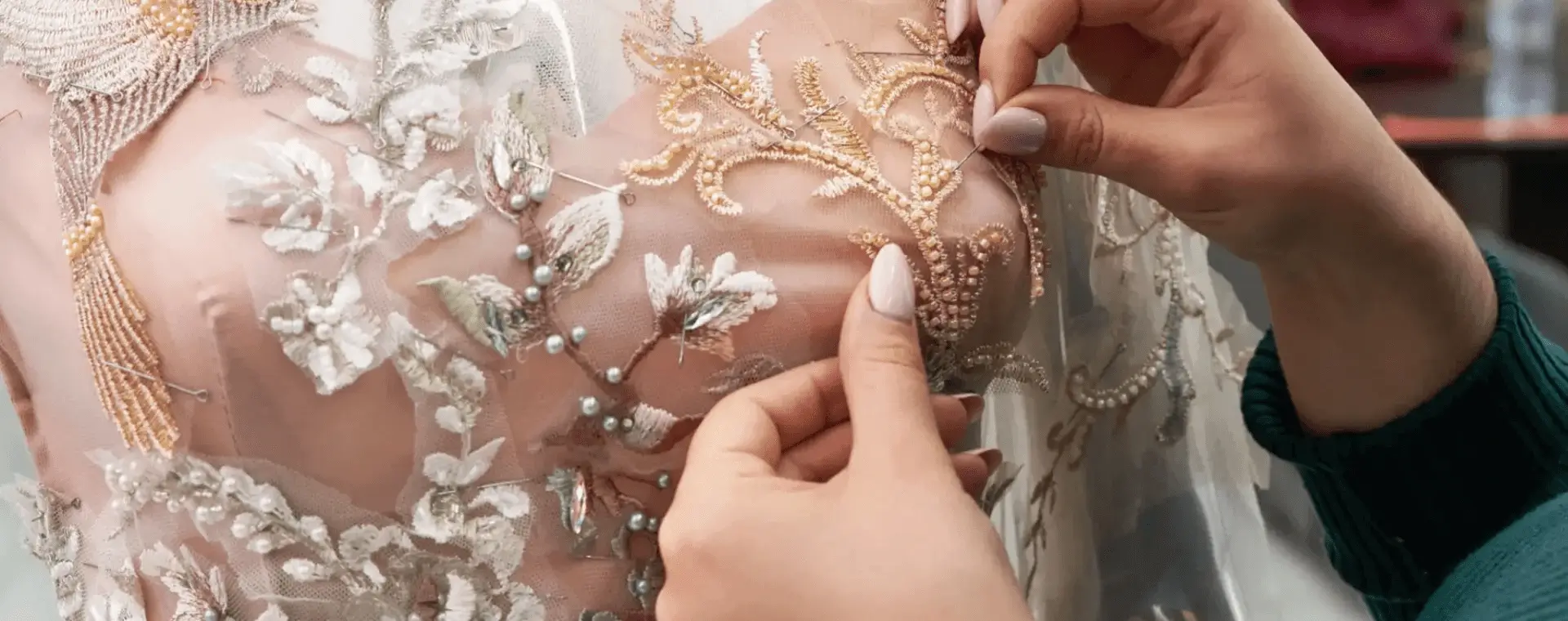 Hands sewing intricate embroidery on fabric.