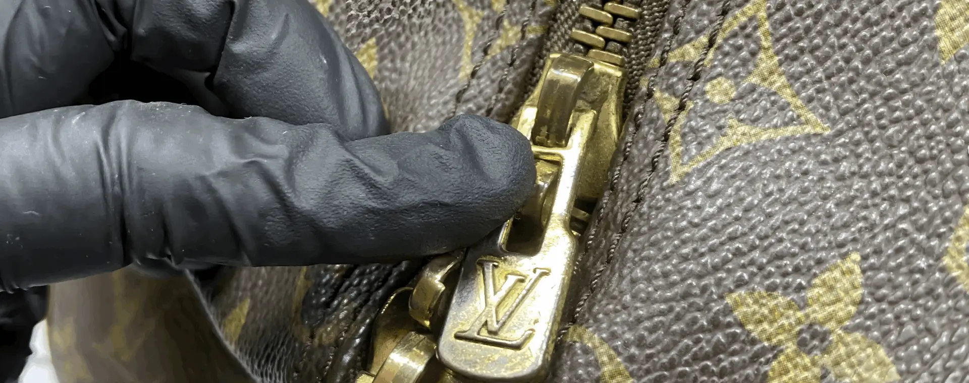 Black glove touching designer bag zipper